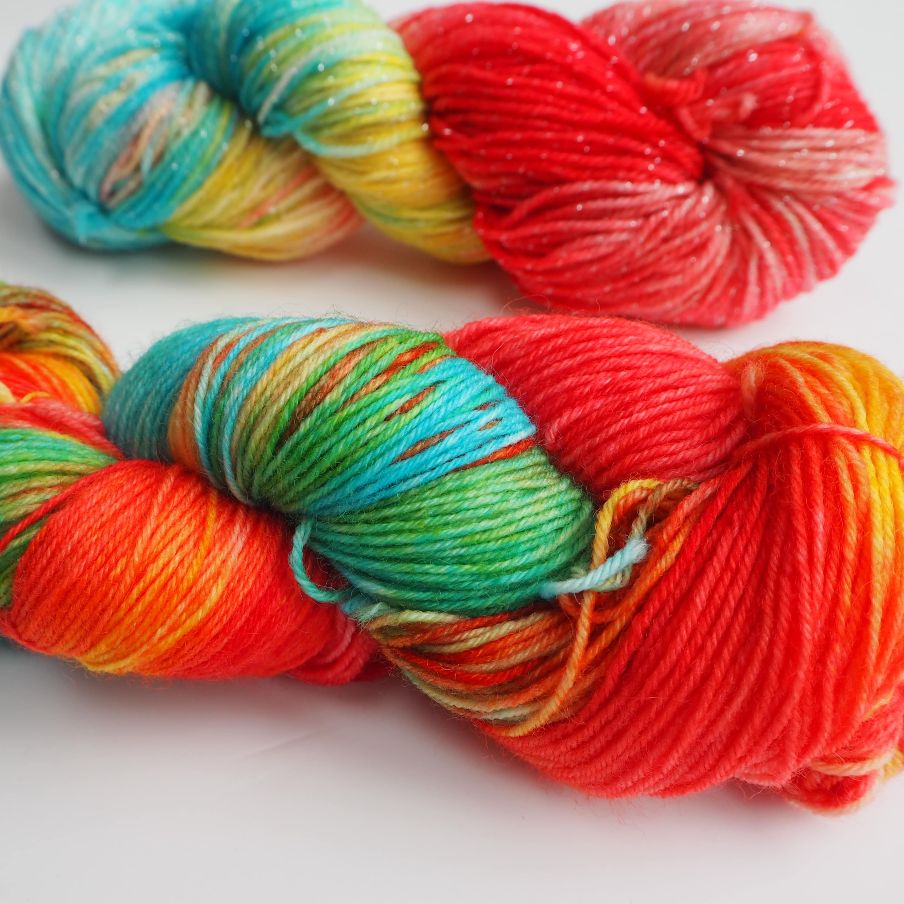 two skeins of hand dyed yarn in bright yellow, blue and red colours