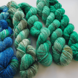 hand dyed gradient mini skeins of merino lurex yarn in blue and green colours with moss speckles