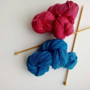 red and blue hand dyed yarn with knitting needles