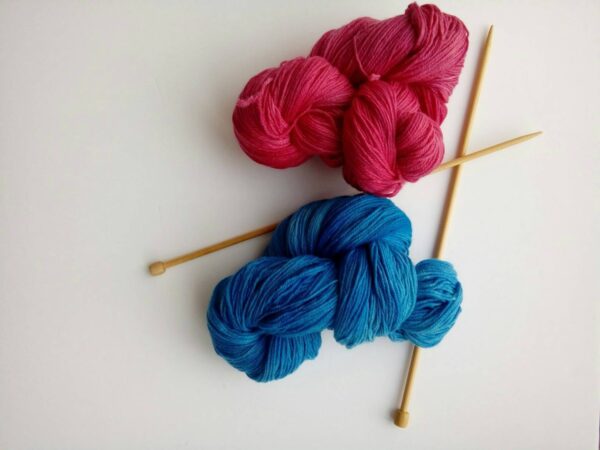 red and blue hand dyed yarn with knitting needles