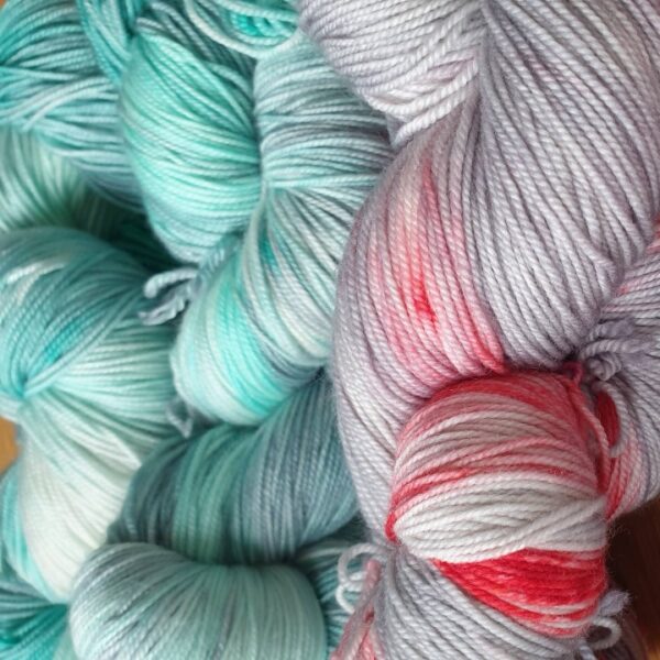 hand dyed skeins of yarn in grey and green on the left and grey with red stains and speckles on the right