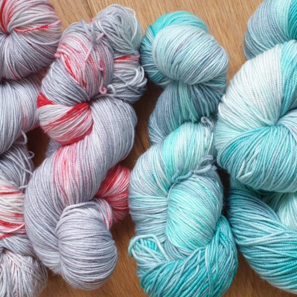 skeins of hand dyed yarn in grey and red on the left and grey and green on the right