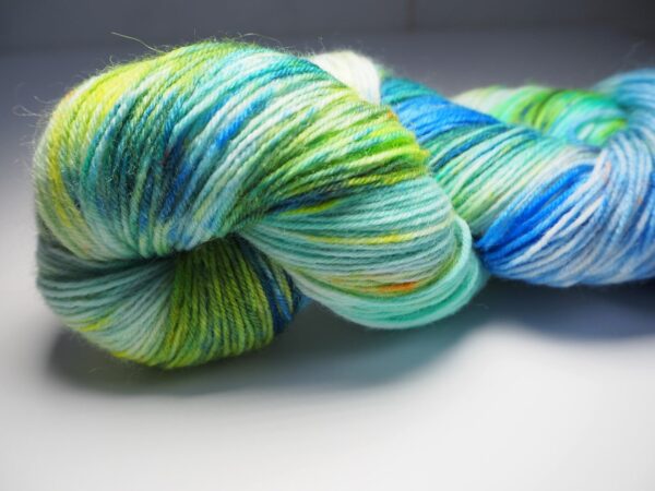 hand dyed yarn skein in blue and green with yellow and brown speckles